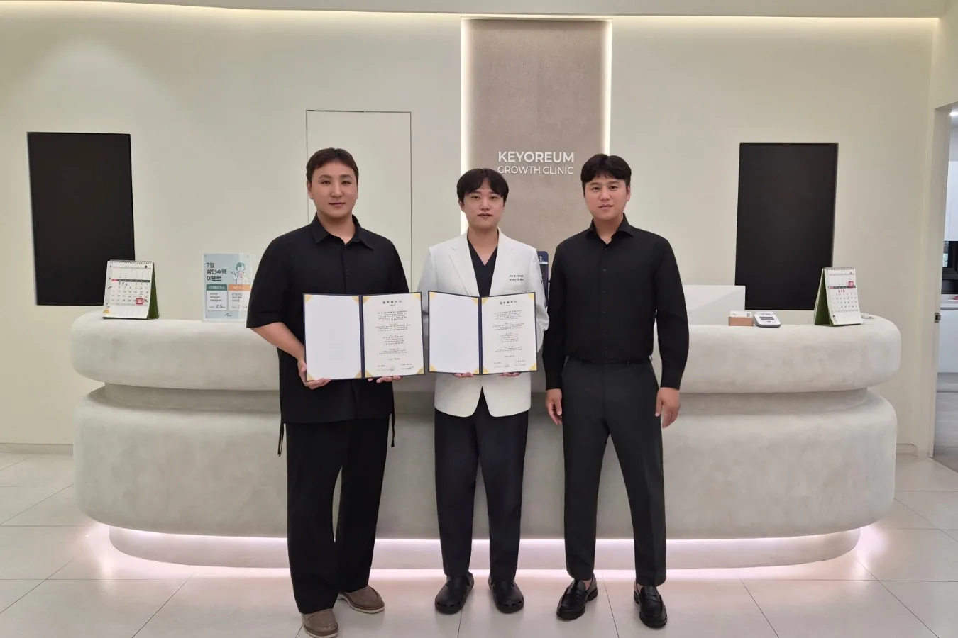 키오름성장의원 로비에서 업무협약서를 들고 선 무브태권도장과 키오름성장의원 관계자